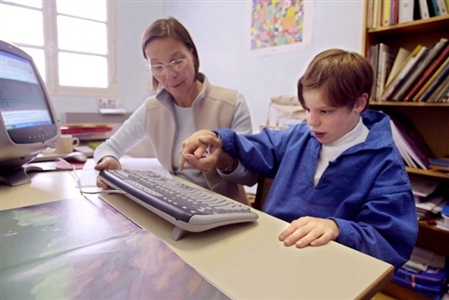 Un enfant autiste tente d'écrire sur un ordinateur avec une orthophoniste ...(Archives 2005) ©AFP/Joël Robine