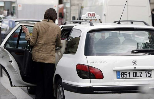 Un taxi parisien en passe de prendre une cliente dans la rue