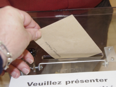 Un homme glissant l'enveloppe contenant son bulletin dans l'urne dans la 3e circonscription de Toulouse