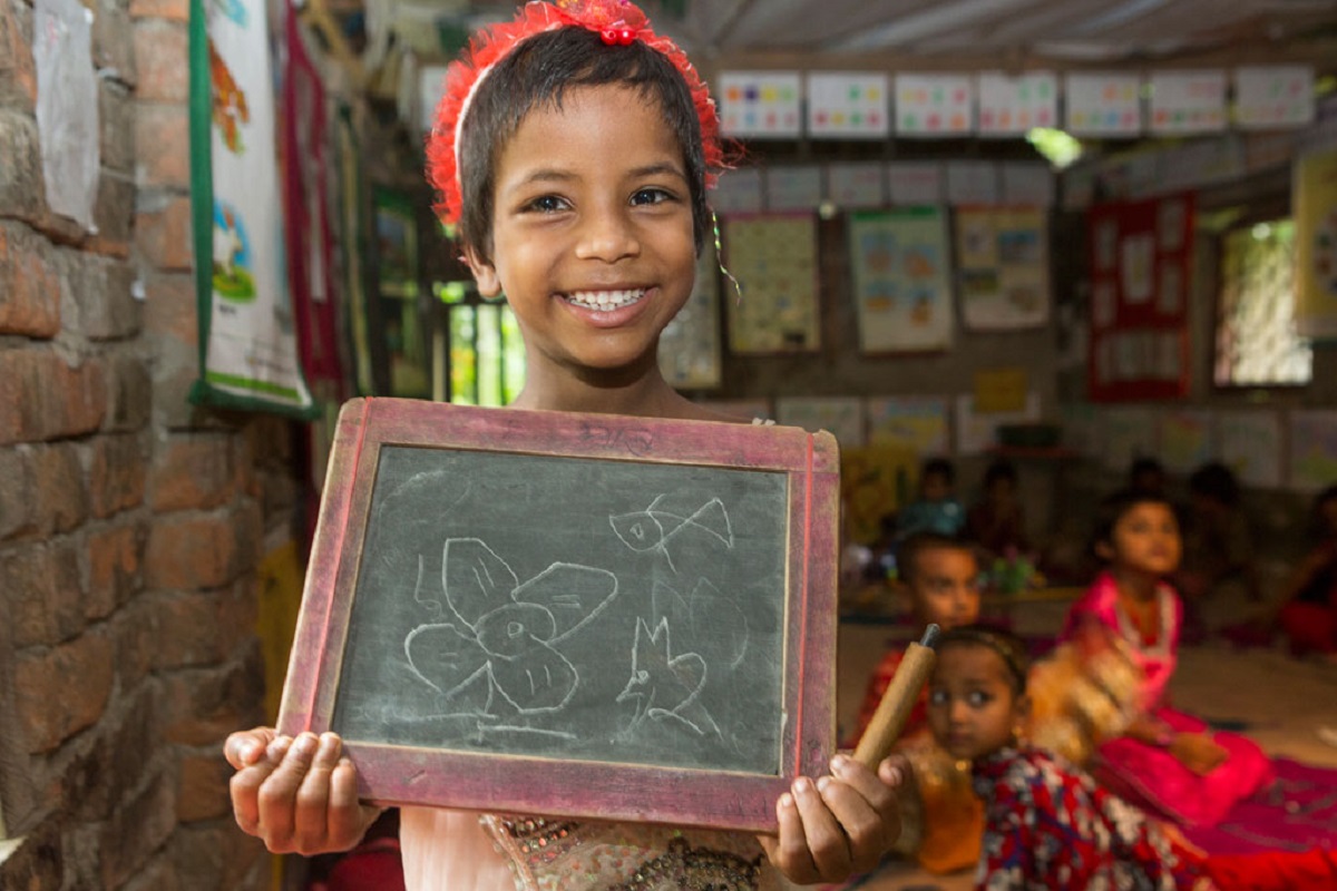 Un enfant handicape qui tients heureusement une ardoise lors d un cours de classe a l ecole