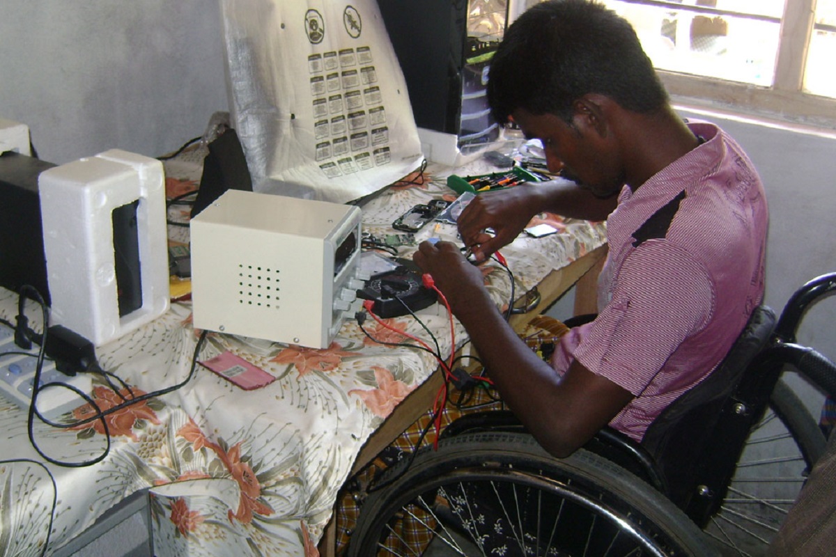 Un homme handicape qui repare un telephone portable au Sri Lanka