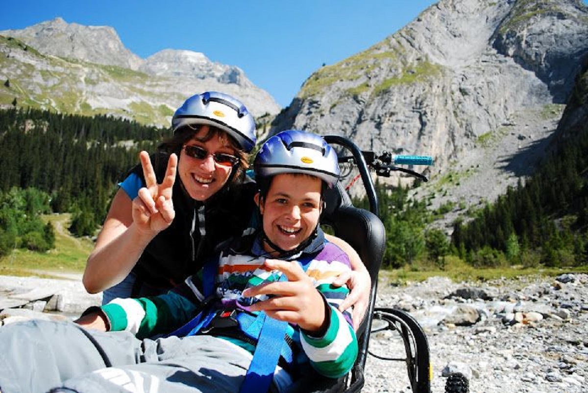 Une femme et un jeune garcon en fauteuil decouvrant le site en randonnee
