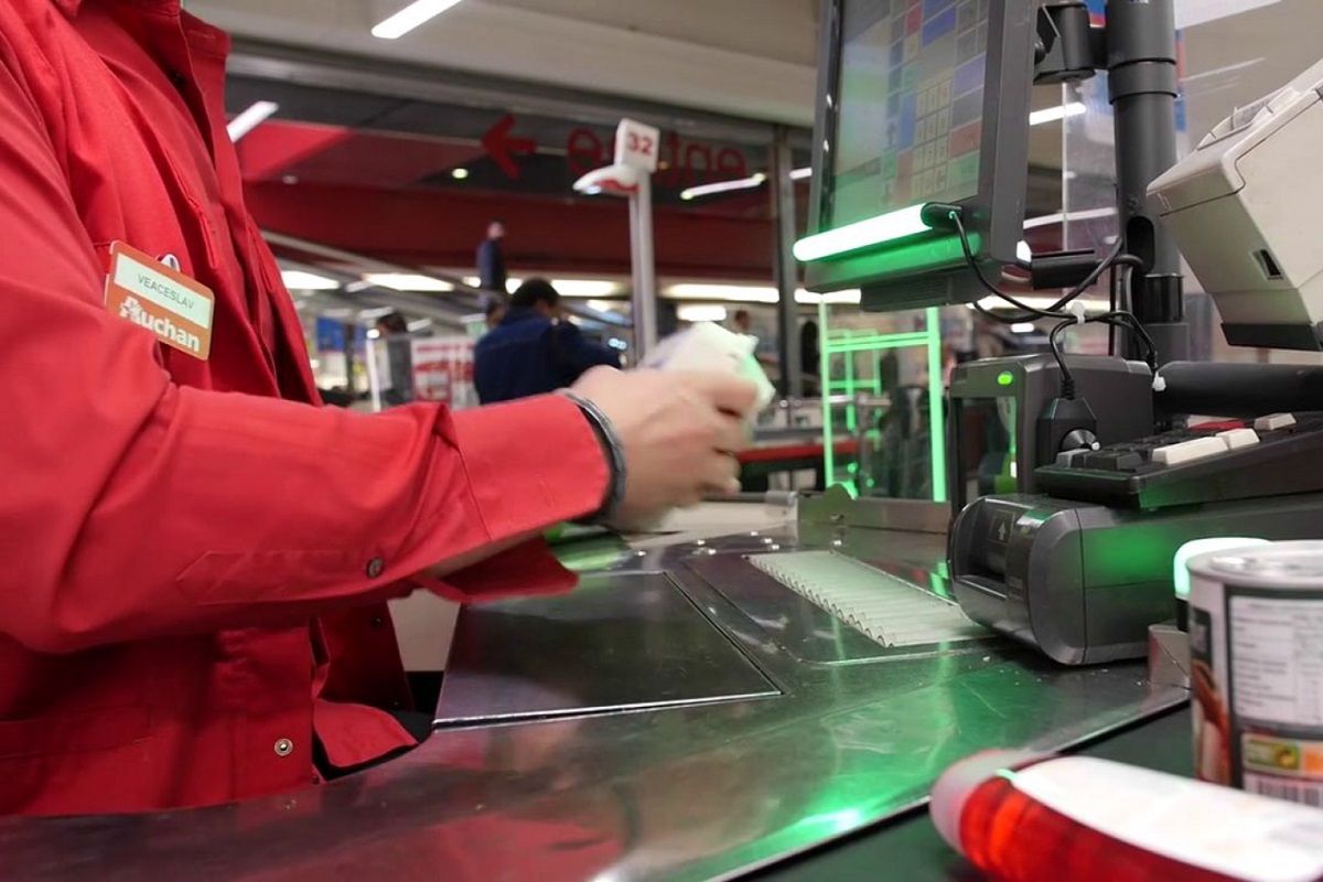 un salariés déficient auditif à la caisse au sein de lentreprise auchan beneficiant du systheme lumicaisses eb822