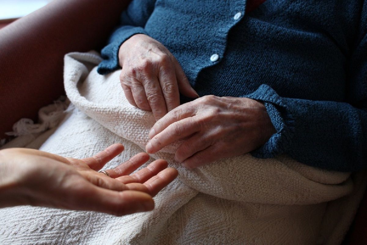 Une femme âgée en perte d'autonomie et en fauteuil en compagnie d'un aidant