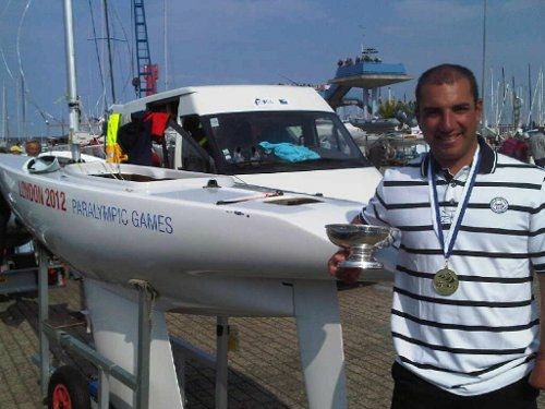 Damien coupe a la main, devant son bateau, dejà au couleur des jeux paralympique de Londres 2012, remportant ici la Kieler Woche en Allemagne © DR