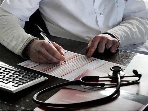 Un Médecin lors d'une consultation rédigeant la feuille de soins