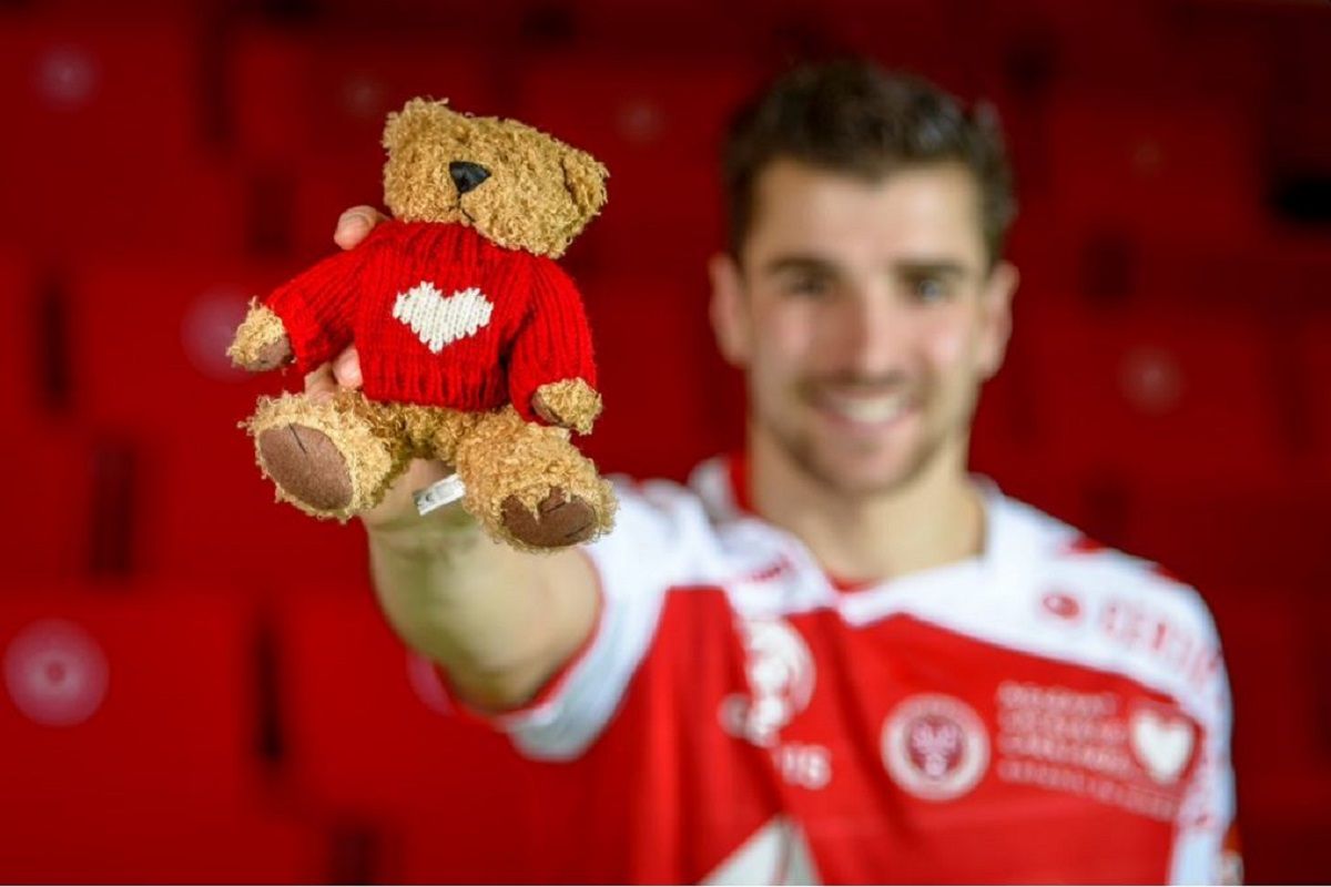 Un joueur du Stade de Reims portant le maillot et la mascotte de l association