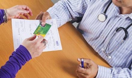 Médecin rendant la carte vitale de sa patiente avec une ordonnance (illustration) © Nathan Alliard/AFP