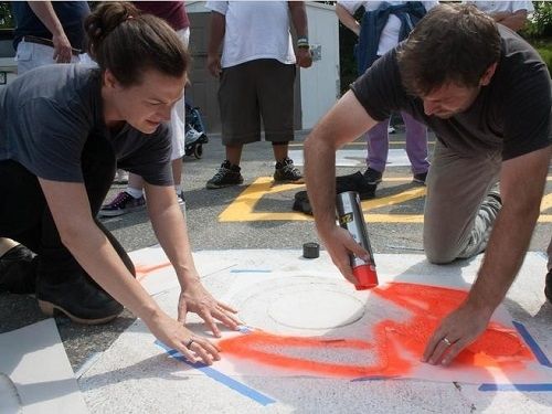 Sara Hendren, concepteur du nouveau symbole de stationnement accessible, et Brian Glenney, un artiste de graffiti r&eacute;form&eacute;e et professeur de philosophie, peinture en a&eacute;rosol le premier espace de stationnement avec le nouveau symbole dans le Triangle Inc. stationnement sur le 10 ao&ucirc;t de &copy;Clarissa Sosin