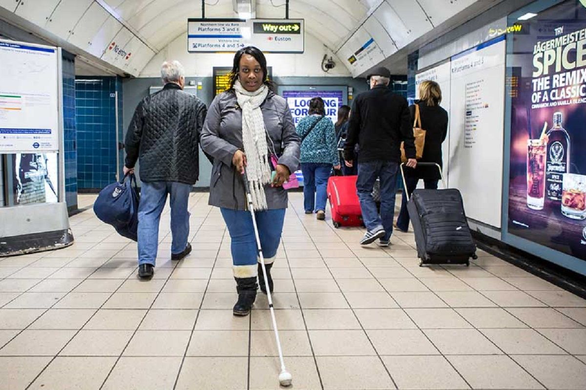 Une personnes malvoyante se deplacant en tout autonomie dans le metro londonnien accessible